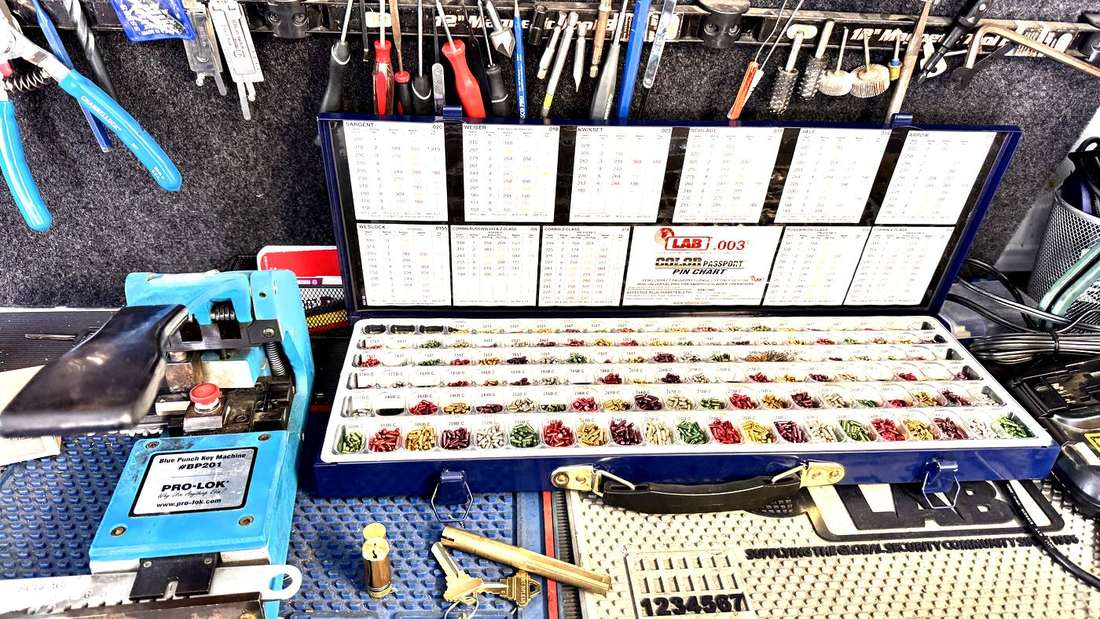 The workbench inside a Diamondback Lock & Key service van: a Pro-Lok key machine, a LAB pinning kit and pin chart, and tools on the rail above.