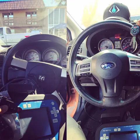 A key programmer plugged into a Subaru dashboard while a new key is set up