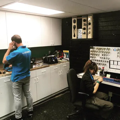 Two Diamondback team members at the shop counter in front of the key wall