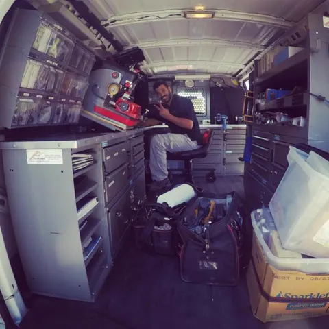 A technician at the workbench inside the service van