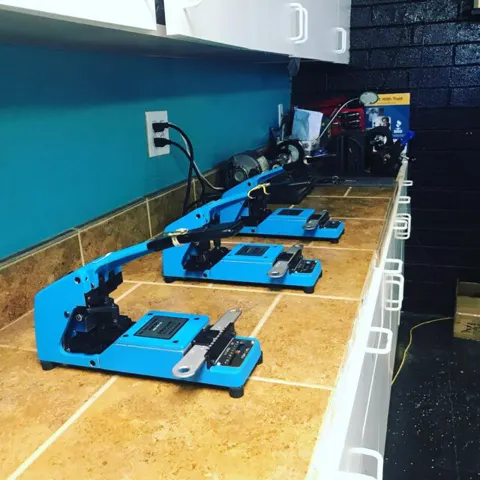 Three blue key-cutting machines on the shop bench