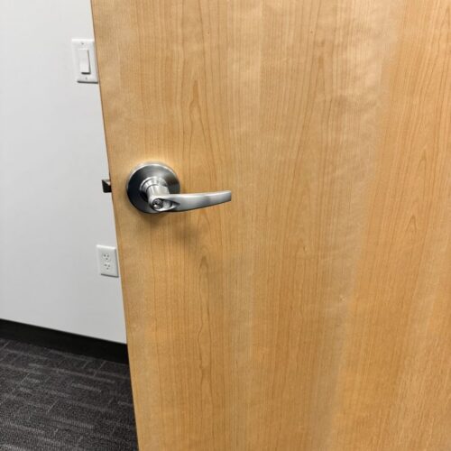 A keyed satin-chrome lever handle fitted to a commercial office door.